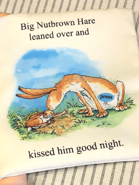Children's book page with illustration of a hare and baby bunny, text 'Big Nutbrown Hare leaned over and kissed him good night.'