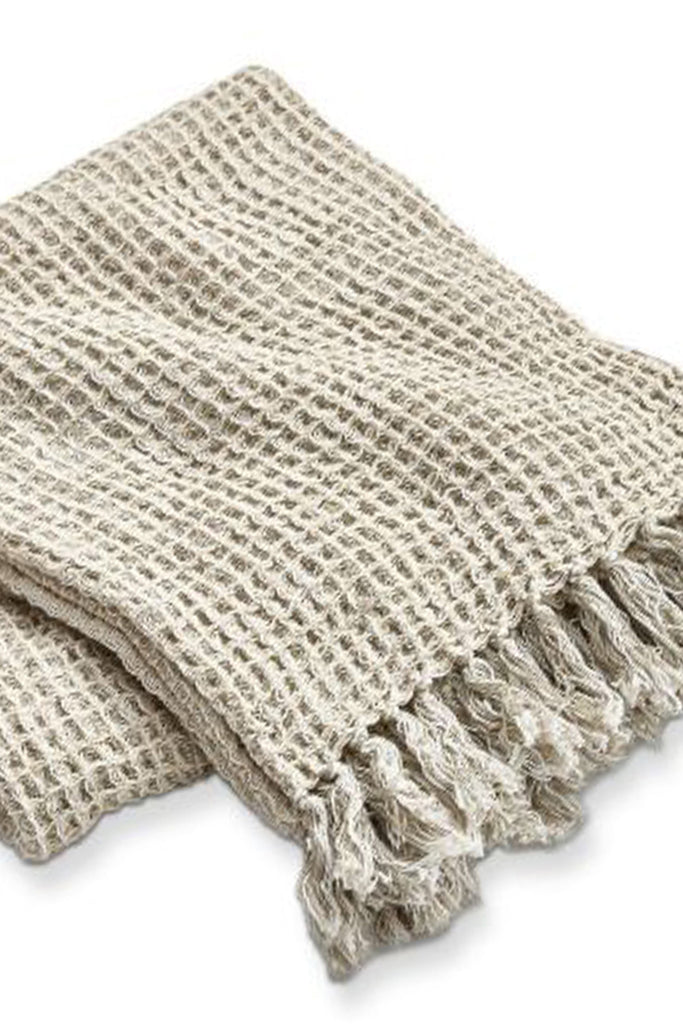 Beige woven blanket with tassels on a white background