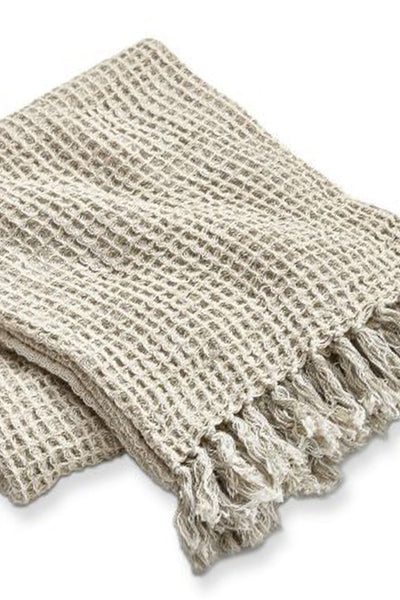 Beige woven blanket with tassels on a white background