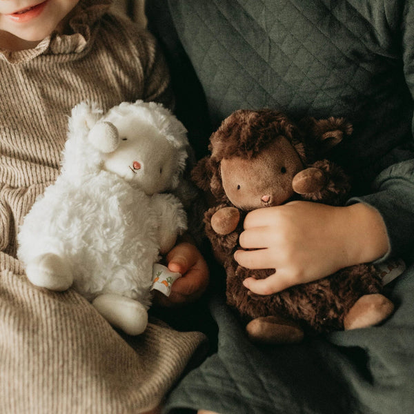 Two children holding White Wee Kiddo and Cocoa Wee Kiddo the lamb stuffed animals.