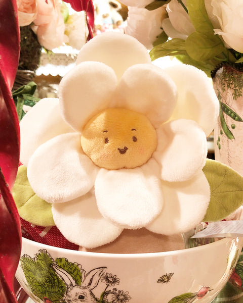 Plush toy shaped like a flower with a face in a bowl surrounded by flowers