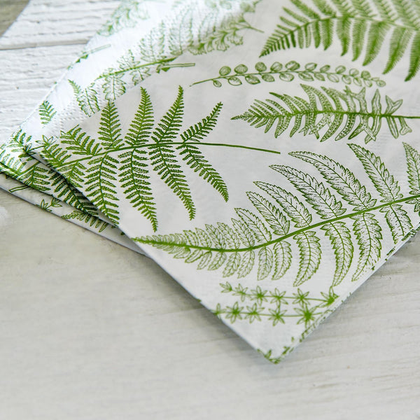Folded paper napkins with green fern pattern on a white background
