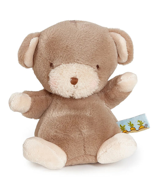 A tiny plush teddy bear toy in light brown with cream-colored snout, inner ears, and paw pads, sitting against a plain white background. A small fabric tag with a carrot illustration is visible on the right side.
