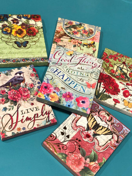 Decorative notebooks with floral and butterfly designs on a teal background