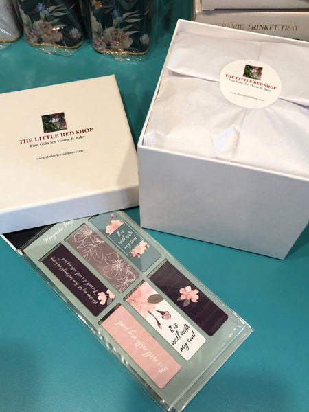 Set of decorative bookmarks in a clear plastic case on a teal surface