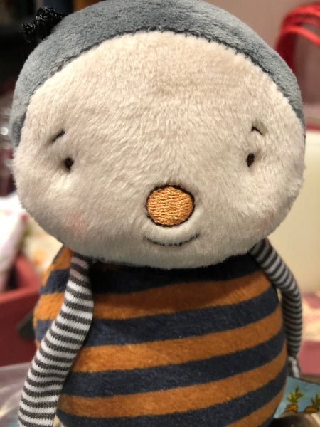 Close-up of a plush toy bee with a round face and striped sleeves.
