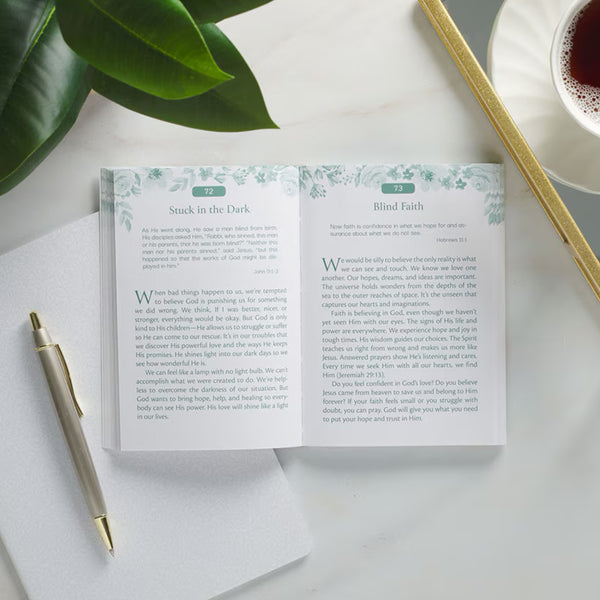 Open book with text on a white surface with a pen and cup of tea