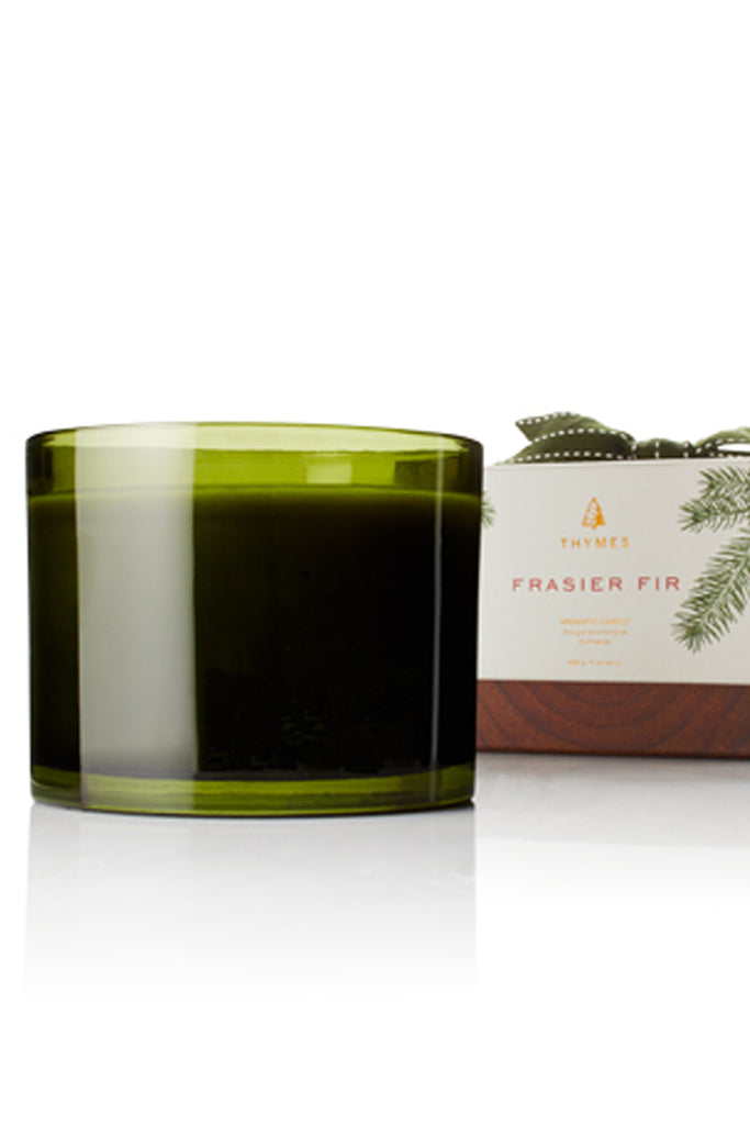 Green candle in a glass jar with a branded box on a white background