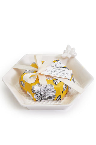 Yellow floral boxed soap with a white ribbon on a hexagonal white dish against a white background