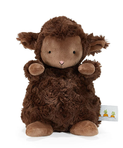 A plush brown sheep toy with curly textured fur, a light brown face, small black eyes, a pink stitched nose, and raised front paws, photographed on a clean white background. A small fabric tag with carrot illustrations is visible near the lower right.