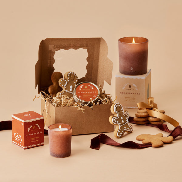 A selection of Thymes Gingerbread Candles shown with gift box & cookies