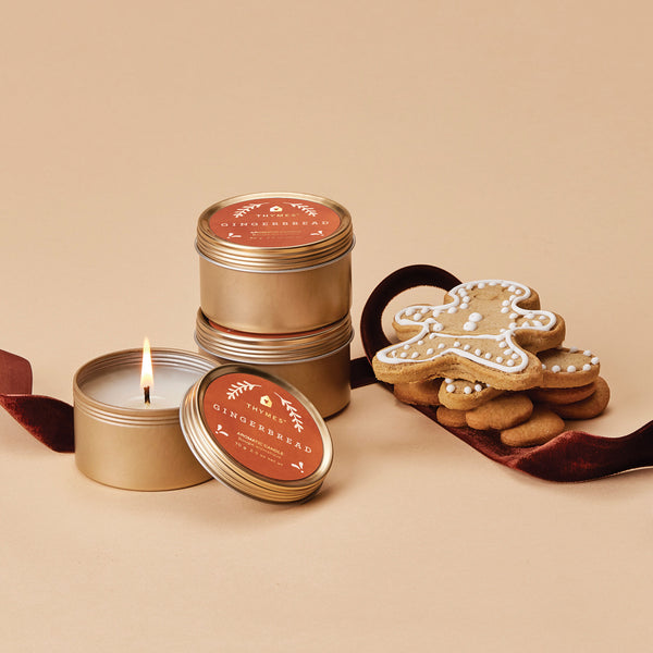 Thymes Gingerbread Travel Candles shown with Gingerbread man cookies. 